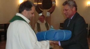 Pfarreiratsvorsitzender Norbert Skowronek überreicht Thomas Fohrmann neben dem Ambo ein großes blaues Geschenk.