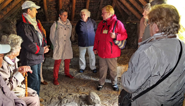 Gemeindemitglieder besichtigen eine Lehmhütte im Moormuseum